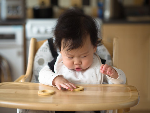 Asian baby girl eating finger food first time