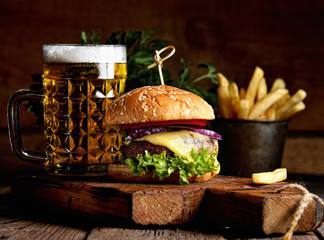 hamburger and mug of beer on wooden table