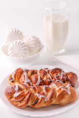 On the table is a plate with two buns, a glass of milk, marshmallows. White background. Mixed light. In high key.
