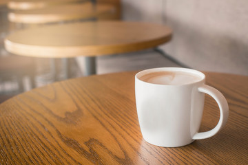 A cup of coffee with heart pattern in a white cup on wooden background. Cup of cappuccino with foam in the form of heart.