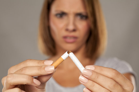 young disgusted woman holding a broken cigarette