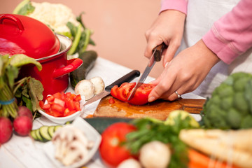 Housewife cutting tomato with a knife