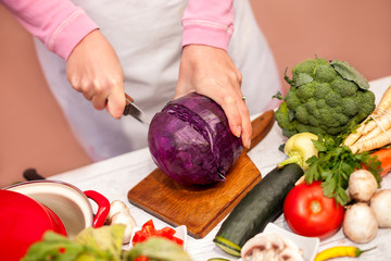 Woman in the kitchen cutting a red cabbage