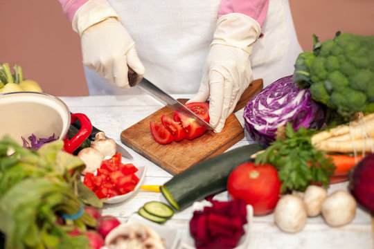 Woman with gloves slicing tomato