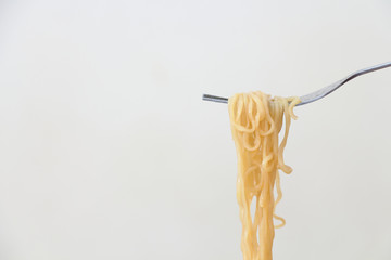 cooked instant noodles holding by a fork on light gray backgroun