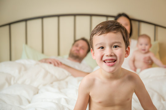Young Mixed Race Chinese and Caucasian Boy Laying In Bed with His Family.