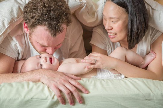 Mixed Race Chinese and Caucasian Baby Boy Laying In Bed with His Father and Mother.