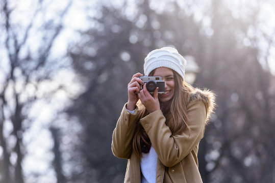 Portrait of winter girl taking photo with vintage camera 