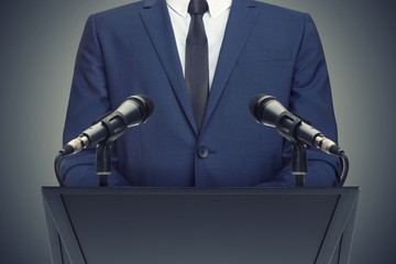 Businessman or politician making speech behind the pulpit - obrazy, fototapety, plakaty