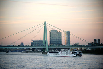 Severinsbrücke Köln / Die Severinsbrücke in Köln während des Sonnenunterganges mit einem passierenden Passagierschiff.