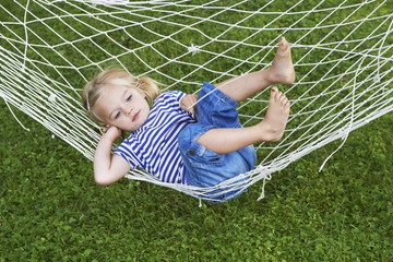 Summer vacation - lovely girl relaxing in hammock in the garden

