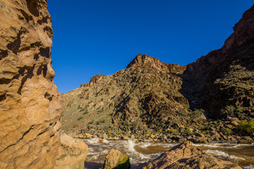Colorado River rapids with rocks in foreground