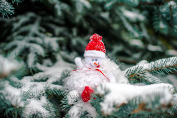 Christmas background Snowman sitting on snow-covered branches of a Christmas tree