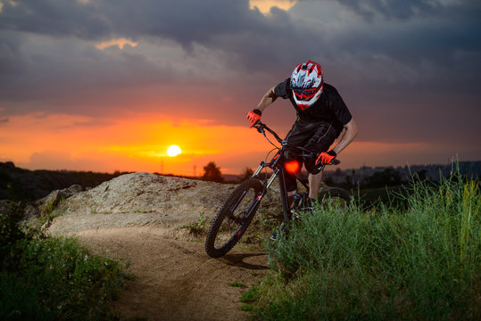 Professional Cyclist Riding the Bike on the Mountain Rocky Trail at Sunset. Extreme Sport