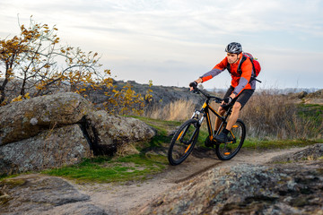 Fototapeta na wymiar Cyclist in Red Jacket Riding the Bike on Rocky Trail. Extreme Sport.