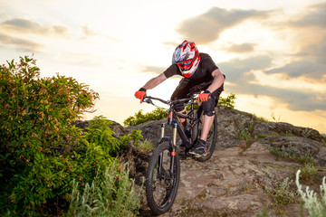 Fototapeta na wymiar Professional Cyclist Riding the Bike Down Rocky Hill at Sunset. Extreme Sport.