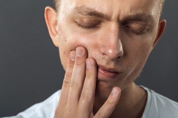 Naklejka premium Close up portrait of a handsome man having toothache standing on gray background