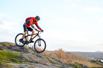 Obraz na płótnie Canvas Cyclist in Red Jacket Riding the Bike Down Rocky Hill. Extreme Sport.