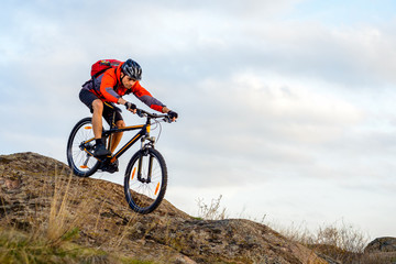 Cyclist in Red Jacket Riding the Bike Down Rocky Hill. Extreme Sport.