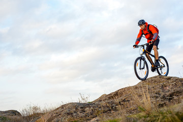 Fototapeta na wymiar Cyclist in Red Jacket Riding the Bike Down Rocky Hill. Extreme Sport.