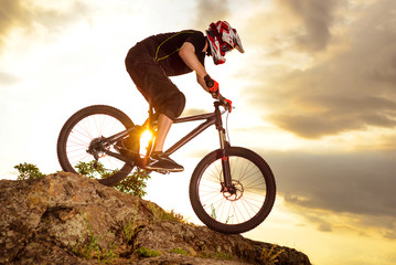 Professional Cyclist Riding the Bike Down Rocky Hill at Sunset. Extreme Sport.