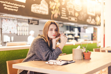 Young cheerful woman posing sitting in cafe