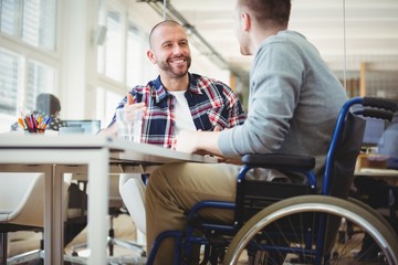Handicap businessman sitting with colleague in office - Powered by Adobe