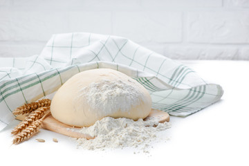 Ball of raw dough isolated on white wooden table with ears wheat and napkin. Copy space.