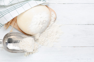 Ball of raw dough isolated on white wooden table with ears wheat and napkin. Copy space. Top view.