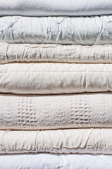 A stack of neatly folded blankets in light colors