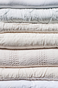 A Stack Of Neatly Folded Blankets In Light Colors