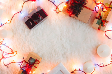 Atmospheric cozy workspace in christmas style with garland, laptop, new year gifts on white fur background. Flat lay, top view. Work on holidays concept