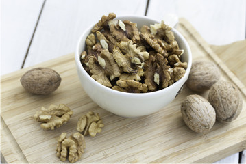 Shelled walnuts in bowl on wooden background