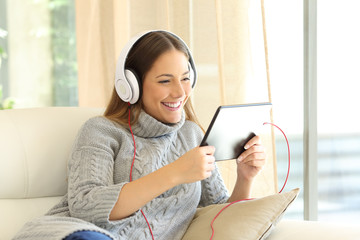 Girl listening music with a tablet at home in winter