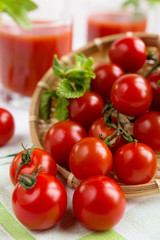 Tomato juice in a glass with a cherry and mint on a light background