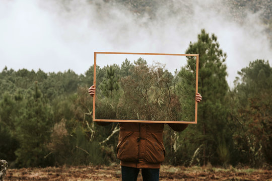 young holding frame with nature, concept of environment