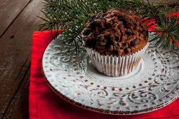 Christmas baking, one chocolate muffin on a plate, surrounded by decorations and Christmas tree branches