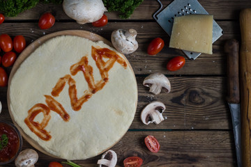 Pizza dough with ingredients on wood