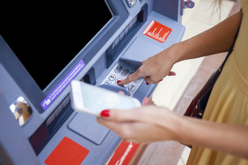 Obraz premium Close up of hand entering pin at an ATM. Finger about to press a