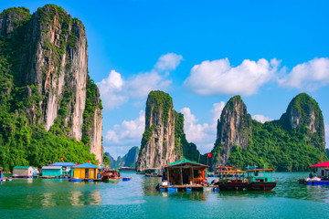 Floating fishing village and rock island in Halong Bay, Vietnam, Southeast Asia. UNESCO World Heritage Site. Junk boat cruise to Ha Long Bay. Landscape. Popular landmark, famous destination of Vietnam - obrazy, fototapety, plakaty