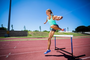 Obraz premium Female athlete jumping above the hurdle