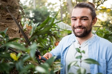 Portrait of confident gardener using hedge clippers at garden