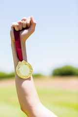 Fototapeta na wymiar Hand of female athlete holding gold medal