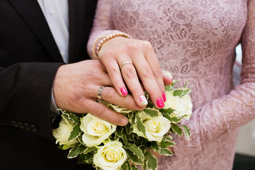 Hands with wedding rings and flower bouquet