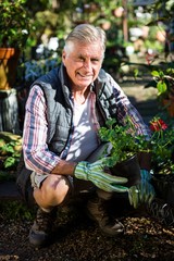 Happy gardener crouching with potted plants 