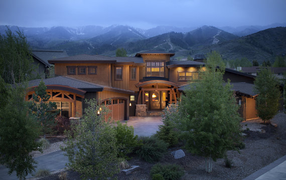Residential home in the Utah mountains, at dusk with ski slopes in background.