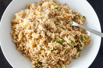 A serving of dirty rice, a traditional cajun and creaole dish, in a white bowl with a fork