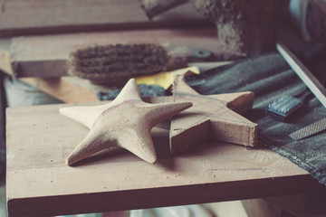 Dark toned photo of the workshop: making wooden stars from tulip tree; unfinished stars, files,...