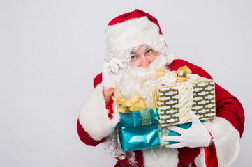 Santa holding many Christmas gifts