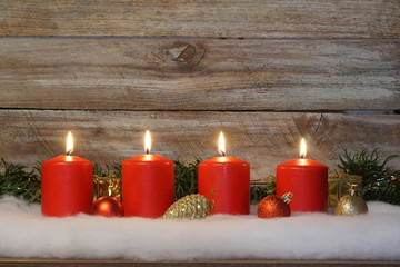 Vier brennende rote Kerzen vor Holz Hintergrund